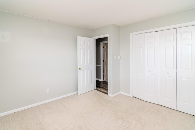 unfurnished bedroom with light colored carpet and a closet