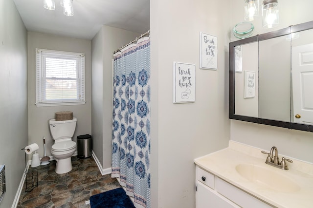 bathroom featuring vanity, walk in shower, and toilet