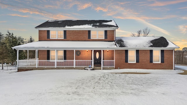 snow covered rear of property featuring a porch