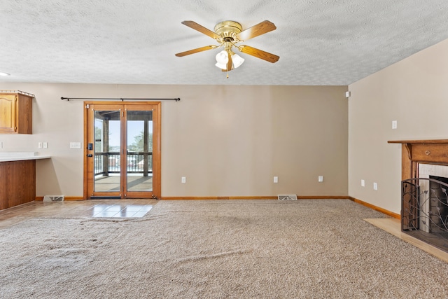 unfurnished living room with light colored carpet, a fireplace, and a textured ceiling