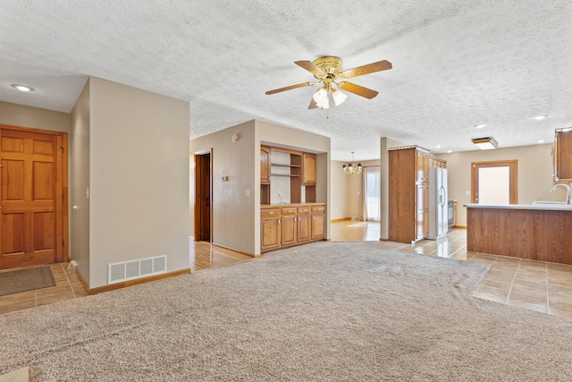 unfurnished living room featuring light tile patterned floors, visible vents, a sink, and light colored carpet