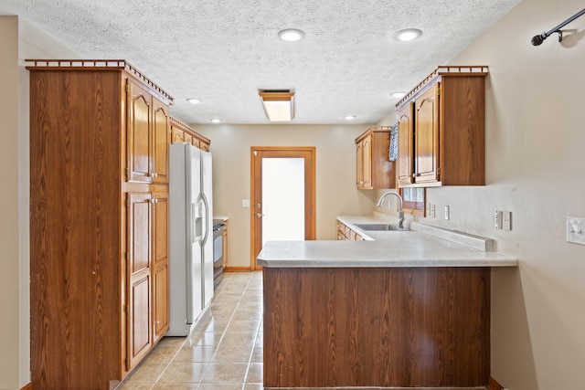 kitchen with white refrigerator with ice dispenser, a peninsula, light countertops, a sink, and light tile patterned flooring