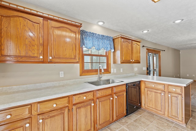 kitchen featuring a peninsula, a sink, black dishwasher, light countertops, and brown cabinetry