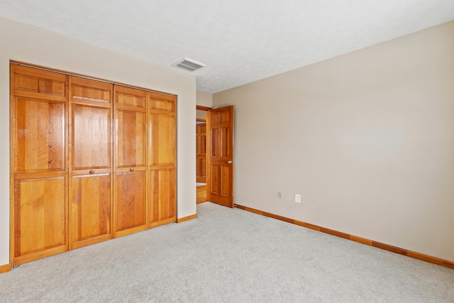 unfurnished bedroom with a textured ceiling, visible vents, baseboards, a closet, and carpet