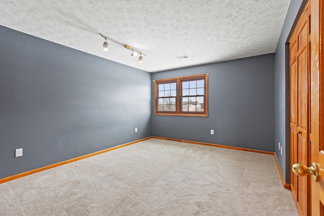 empty room with baseboards, a textured ceiling, and light colored carpet