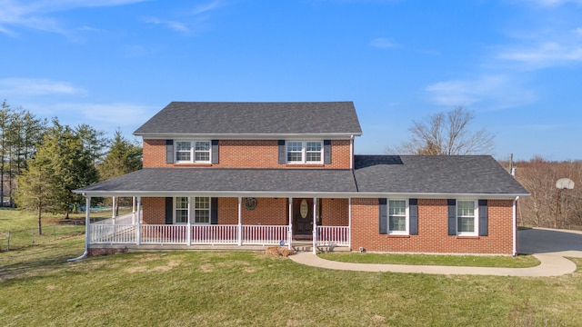 view of front of home featuring a porch, roof with shingles, a front yard, and brick siding