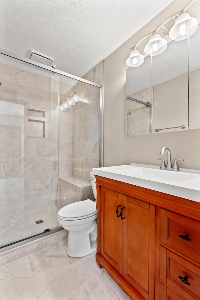 bathroom with vanity, a textured ceiling, a shower with door, and toilet