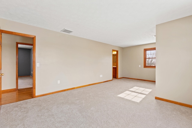 carpeted spare room featuring visible vents and baseboards