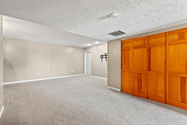 basement featuring light colored carpet and a textured ceiling