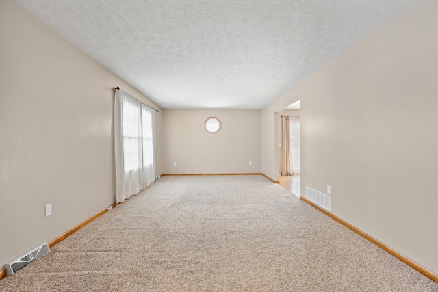 unfurnished room with light carpet and a textured ceiling