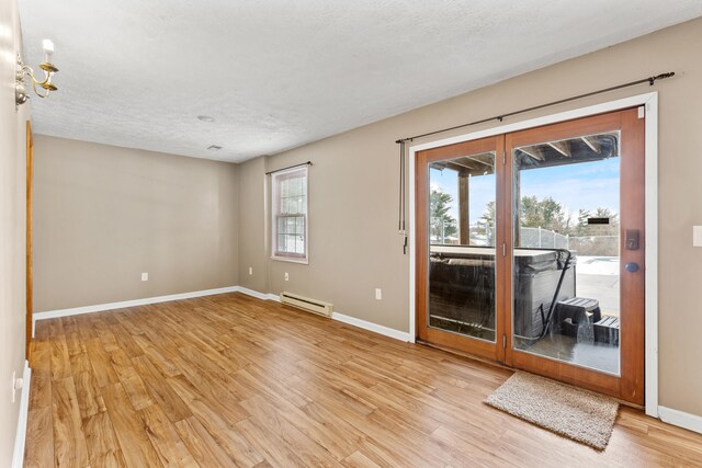 empty room featuring electric panel, light wood-type flooring, a textured ceiling, and a baseboard heating unit