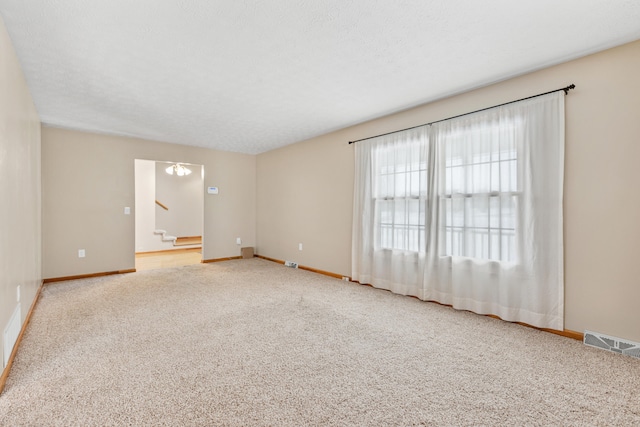 carpeted empty room with visible vents, stairway, baseboards, and a textured ceiling