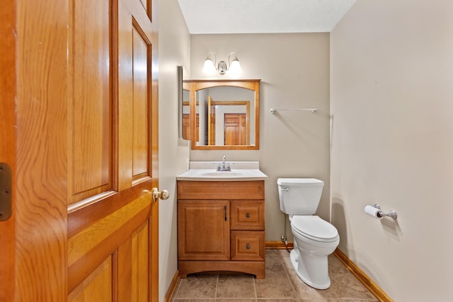 half bath with tile patterned flooring, vanity, toilet, and baseboards