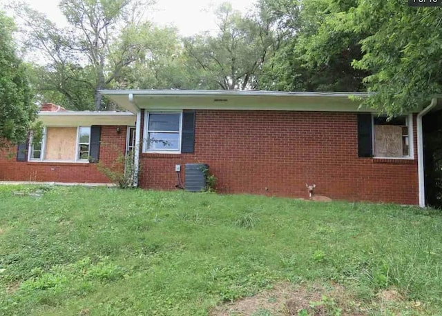 view of side of home with central AC and a yard