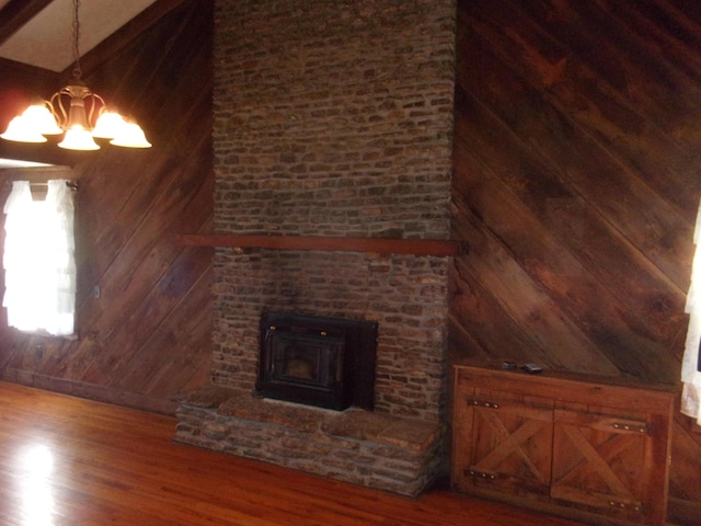 unfurnished living room with wood-type flooring, wooden walls, and a notable chandelier