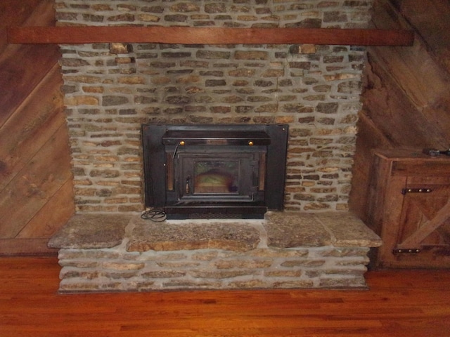 room details with hardwood / wood-style flooring, a wood stove, and wood walls