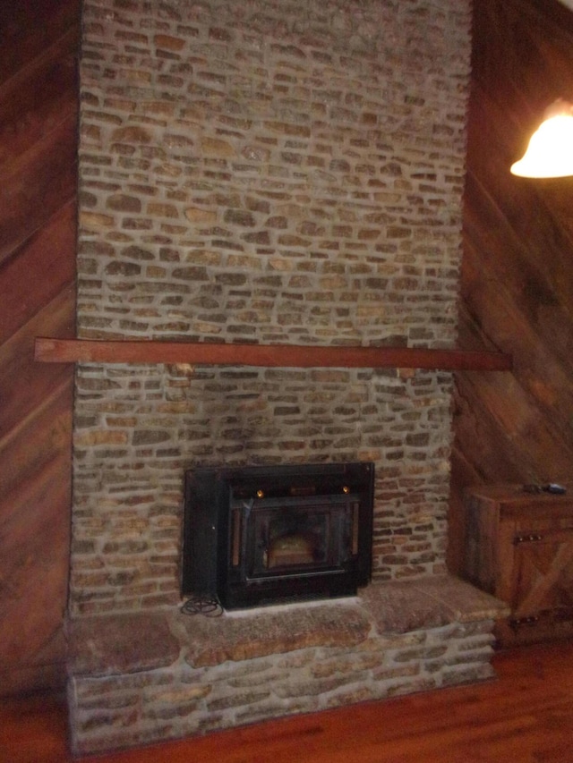 interior details with wood-type flooring, wooden walls, and a wood stove