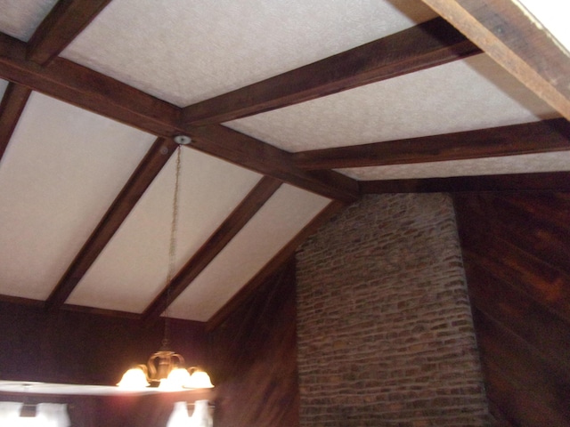 interior details with a notable chandelier, beamed ceiling, and wooden walls