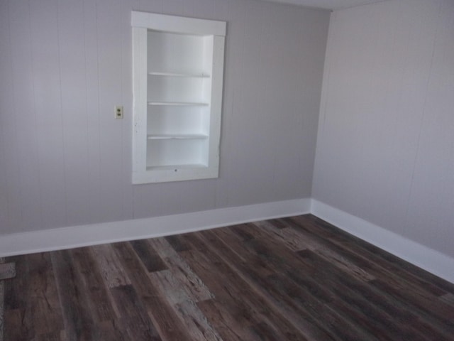 empty room featuring dark hardwood / wood-style floors and built in shelves