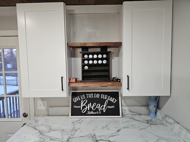 details with open shelves, light stone countertops, and white cabinets