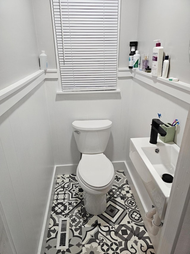 half bath with toilet, visible vents, and wainscoting