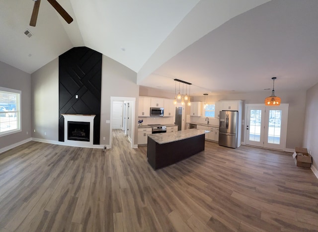 kitchen featuring decorative light fixtures, white cabinetry, stainless steel appliances, and a kitchen island