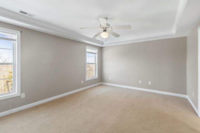 carpeted spare room with a raised ceiling and ceiling fan