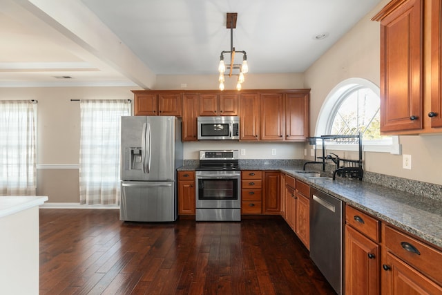 kitchen with sink, decorative light fixtures, dark stone countertops, appliances with stainless steel finishes, and dark hardwood / wood-style floors