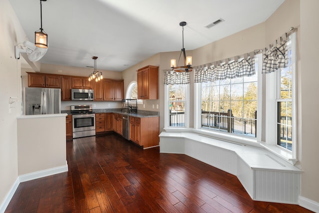 kitchen with dark hardwood / wood-style flooring, a notable chandelier, decorative light fixtures, and stainless steel appliances