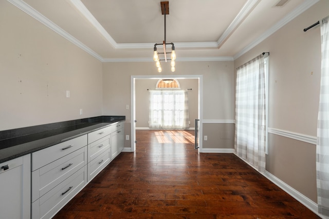 unfurnished dining area featuring dark hardwood / wood-style flooring, crown molding, a raised ceiling, and an inviting chandelier