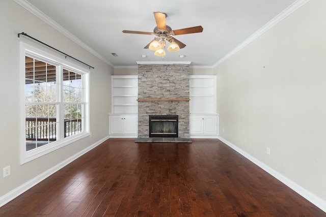 unfurnished living room with ornamental molding, a stone fireplace, built in features, and dark hardwood / wood-style flooring