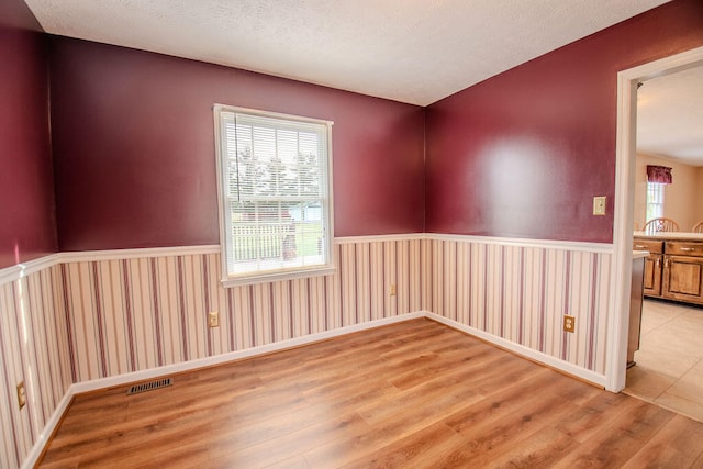 empty room with a textured ceiling and light wood-type flooring