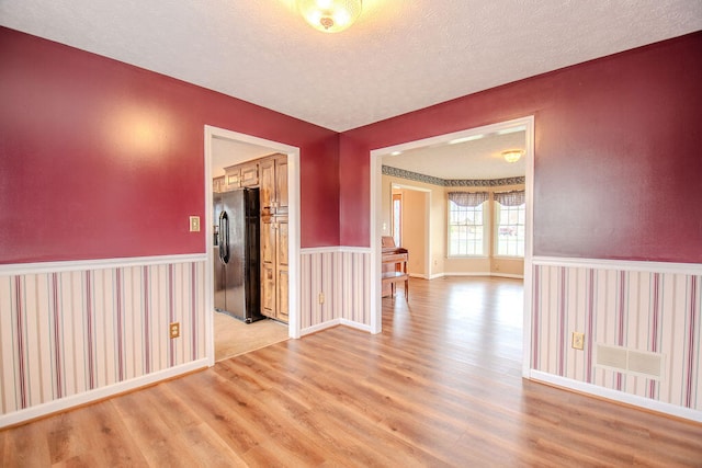 empty room with light hardwood / wood-style floors and a textured ceiling