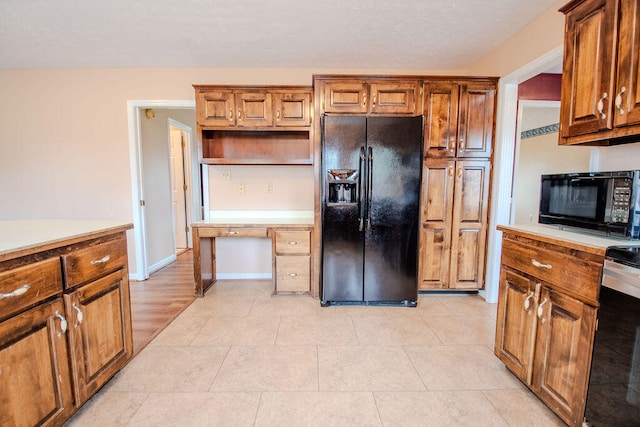 kitchen with built in desk, black appliances, and light tile patterned flooring