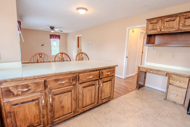 kitchen featuring light tile patterned floors, built in desk, kitchen peninsula, and ceiling fan