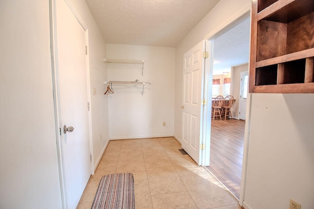 corridor featuring light tile patterned floors and a textured ceiling