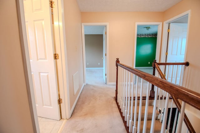 hall with light carpet and a textured ceiling