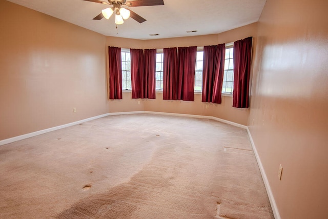 empty room featuring a wealth of natural light, light colored carpet, and ceiling fan