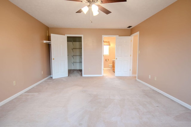 unfurnished bedroom featuring ensuite bath, ceiling fan, a spacious closet, light colored carpet, and a closet