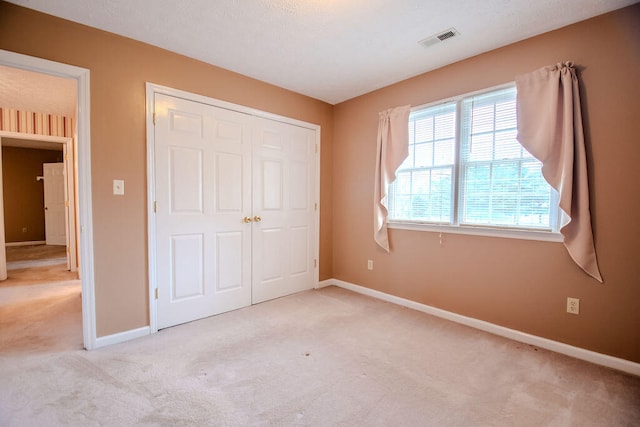 unfurnished bedroom featuring a closet and light carpet