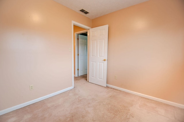 spare room with light colored carpet and a textured ceiling