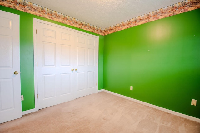 unfurnished bedroom with carpet flooring, a textured ceiling, and a closet