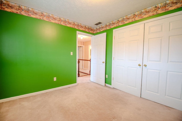 unfurnished bedroom featuring light colored carpet, a closet, and a textured ceiling