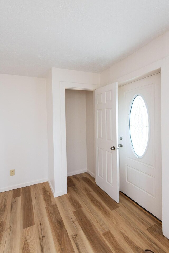 entryway with baseboards and light wood finished floors