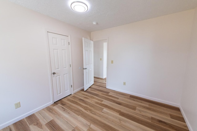 interior space featuring a textured ceiling, baseboards, and light wood-style floors