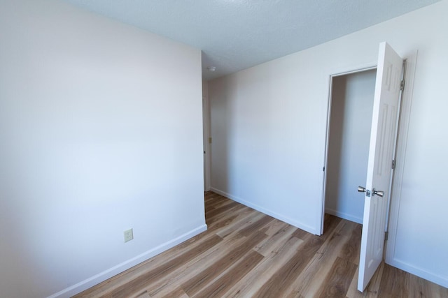 spare room with baseboards and wood finished floors