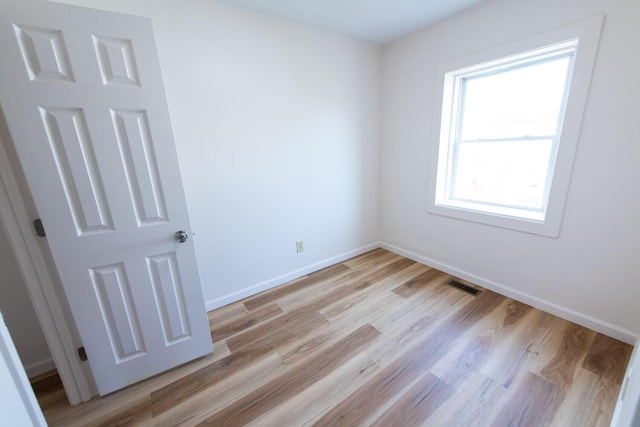 unfurnished room featuring visible vents, light wood-style floors, and baseboards