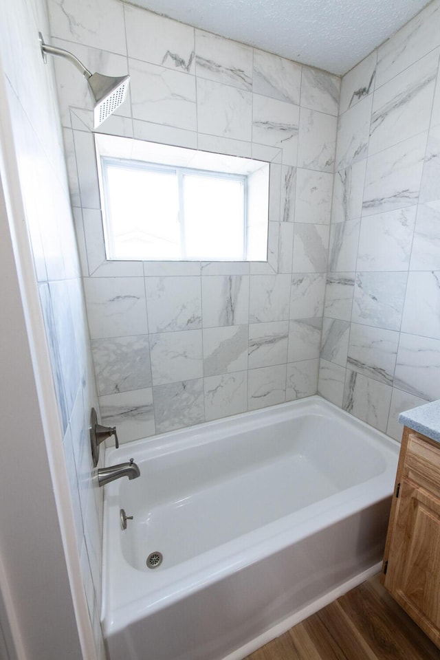 bathroom with bathtub / shower combination, a textured ceiling, wood finished floors, and vanity