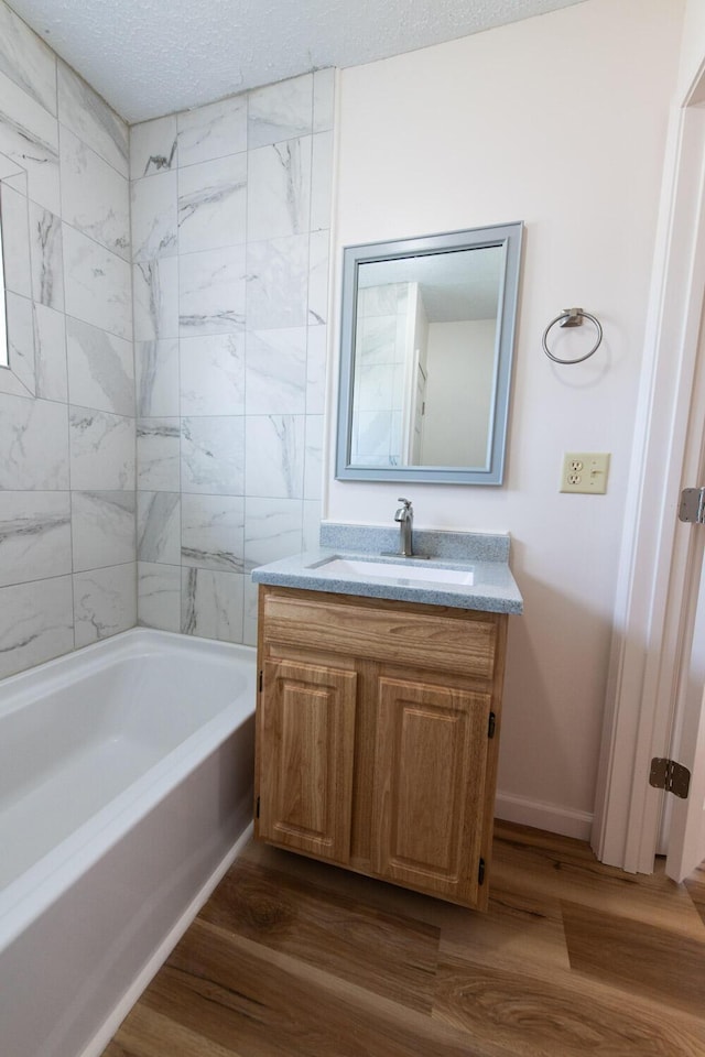 bathroom featuring a textured ceiling, vanity, baseboards, and wood finished floors