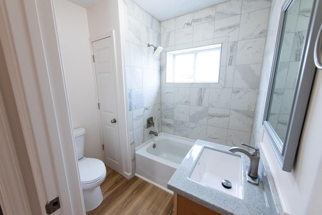 full bath with toilet, vanity, wood finished floors, a textured ceiling, and  shower combination